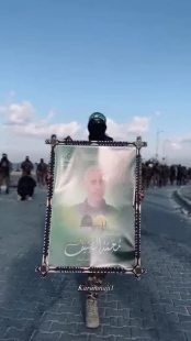 مقاتل من مقاتلي حماس يتجول حاملاً صورة محمد الضيف في ميناء غزة